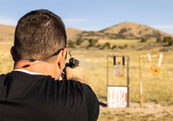 shooter aiming a handgun at a couple targets outside
