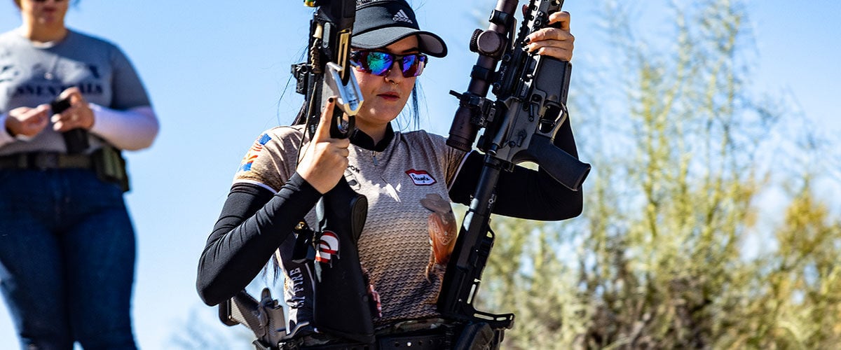 competitive shooter carrying two rifles