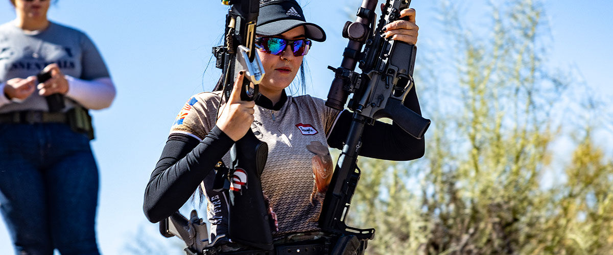 competitive shooter carrying two rifles
