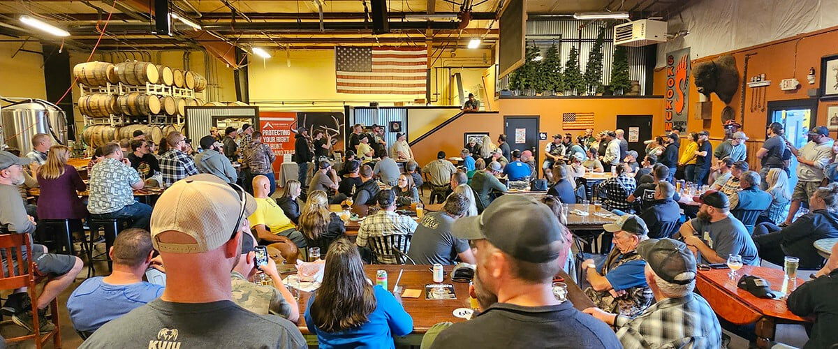 big group of people sitting at tables looking at a speaker