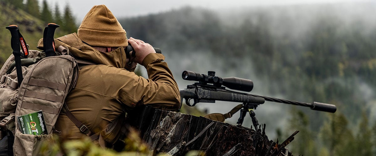 Hunter looking through binoculars on a hill