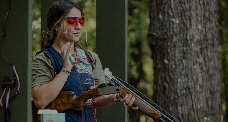 Julia Stallings standing behind a shooting stall and catching ejected shotshells