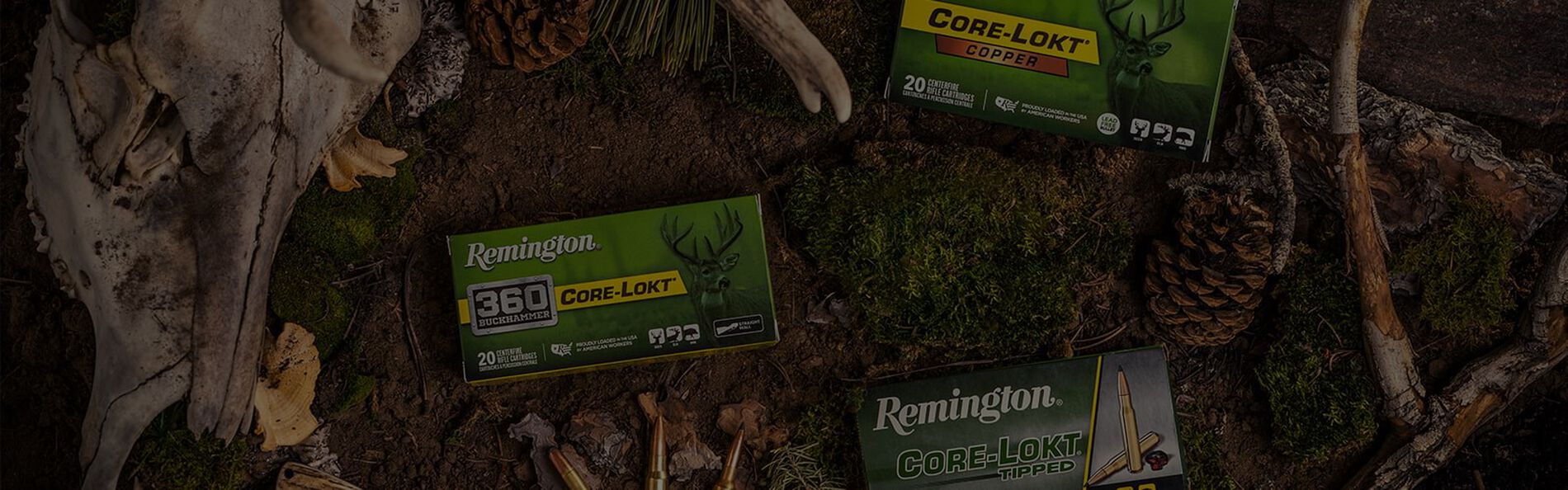Core-Lokt, Core-Lokt Tipped and Core-Lokt Copper packing laying on the ground surrounded by bones, pine cones, sticks, a knife, and cartridges