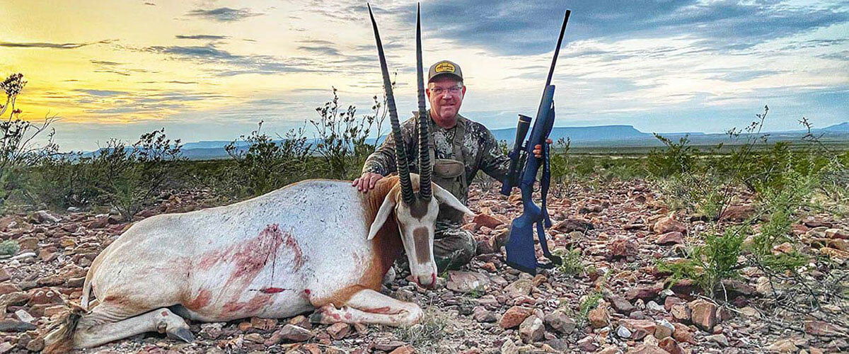 John Langenfeld kneeling beside a dead oryx