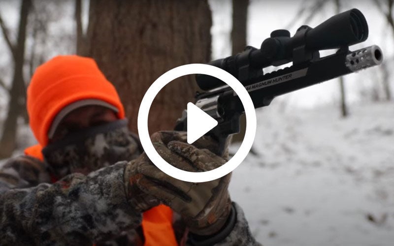 hunter aiming hunting handgun while outside in the snow