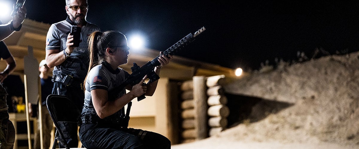person sitting on a chair holding a rifle outside