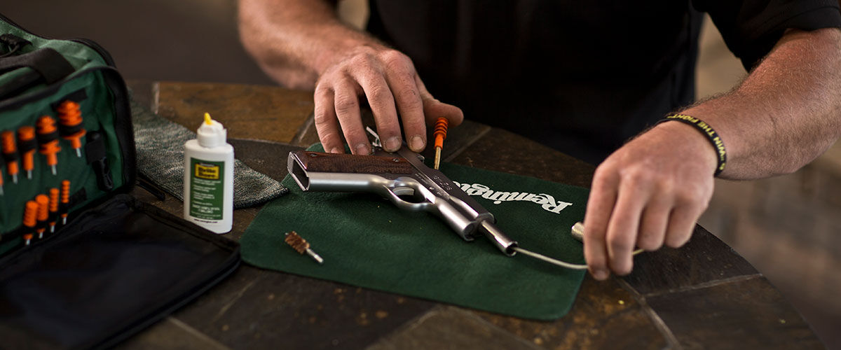 person cleaning a handgun with Remington cleaning accessories