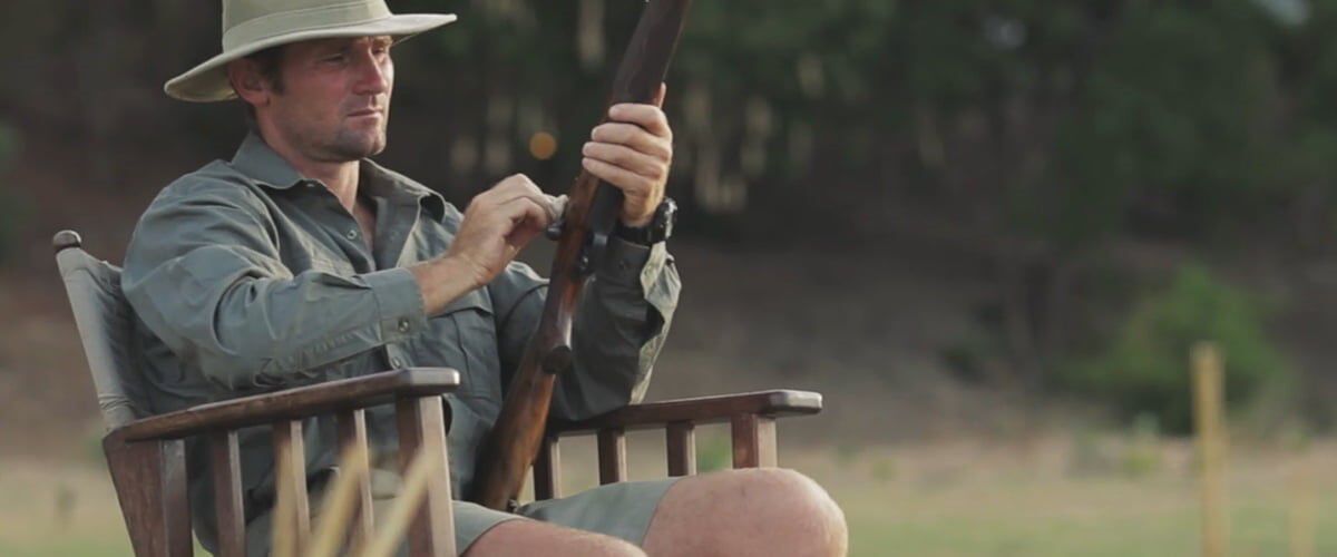 person sitting in a chair and wiping a shotgun