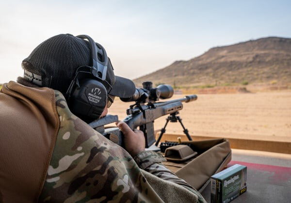 shooter looking down a rifle scope towards a hill far away