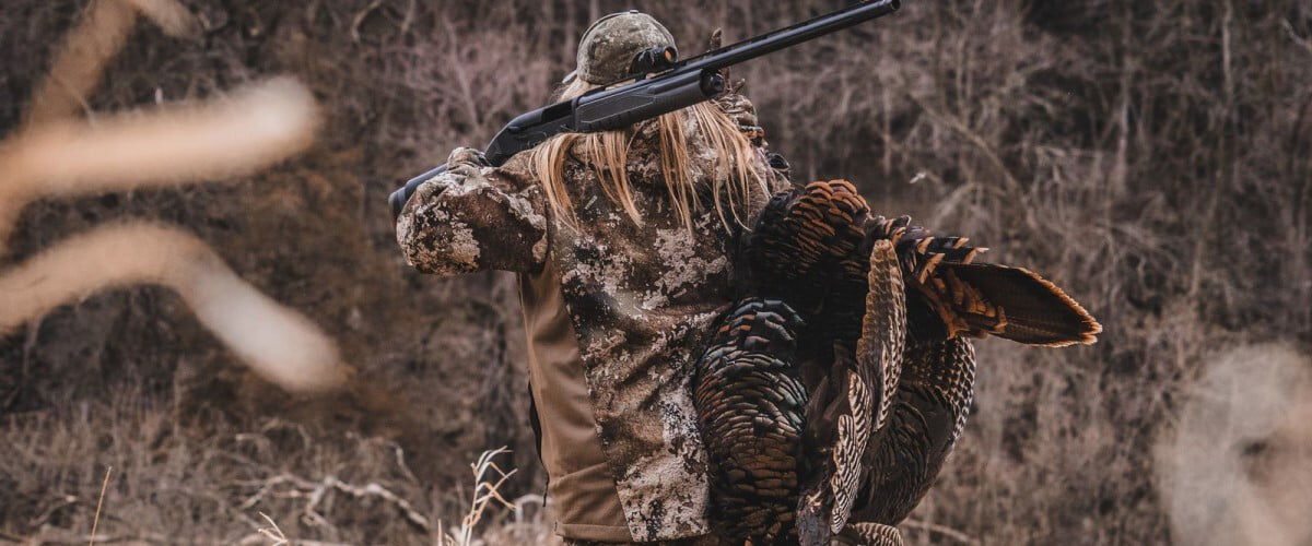 hunter carrying a dead turkey on her back