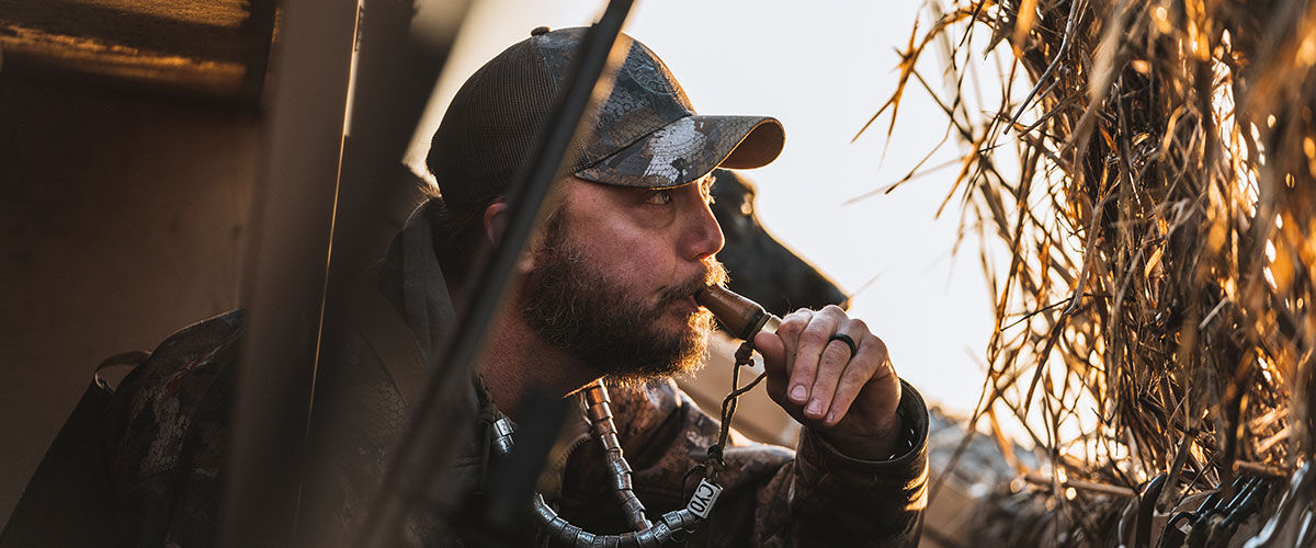 huntering using duck call in a duck blind