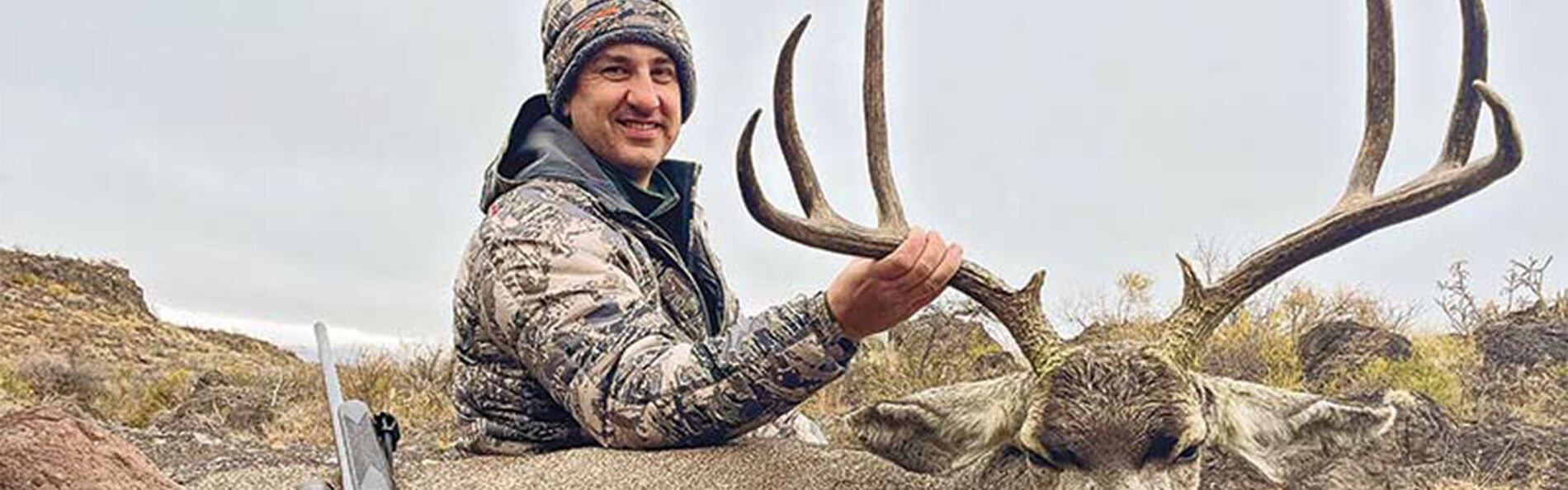 hunter beside a dead deer with his rifle and Core-Lokt Tipped ammunition packaging