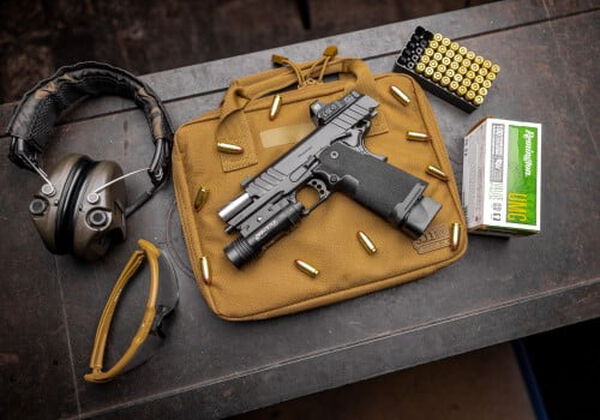 Pistol laying on a pistal bag with Remington UMC cartridges, ear protection, and eyewear