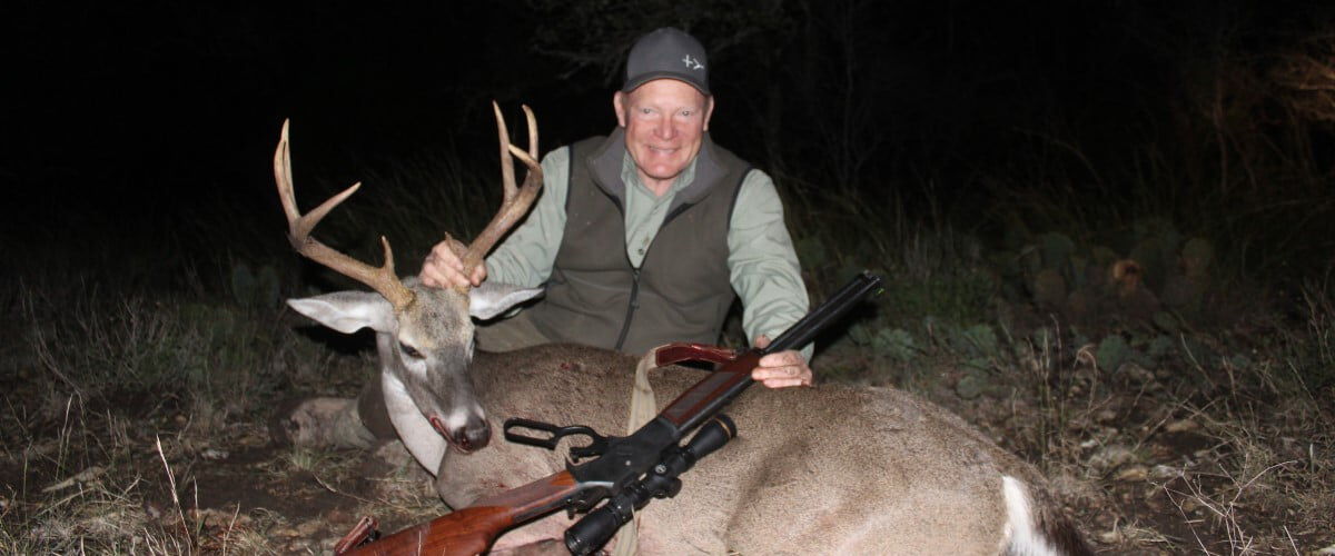 hunter kneeling by a dead deer