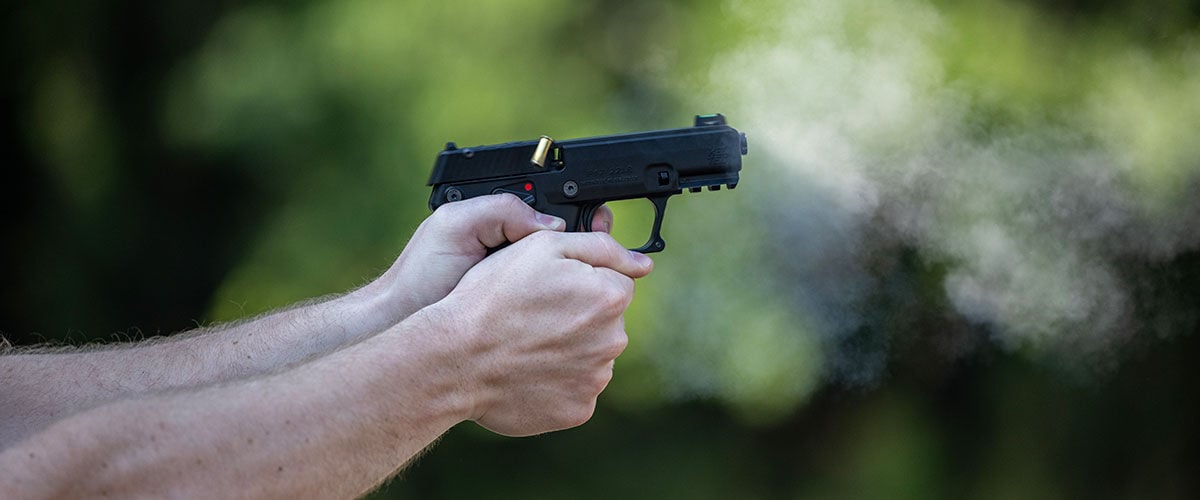 person firing handgun outside