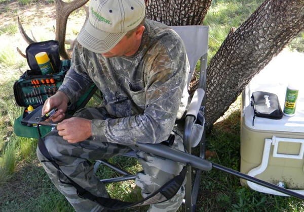 hunting cleaning rifle under a tree