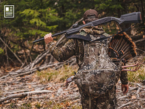 hunter walking with a turkey and his shotgun on his back