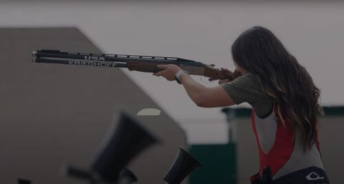 Julia Stallings aiming a shotgun outside
