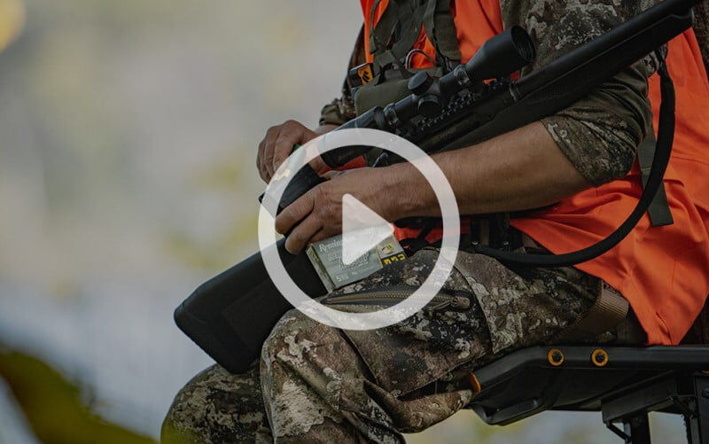 hunter sitting on a tree stand with a shotgun and a box of Premier AccuTip Sabot Slug