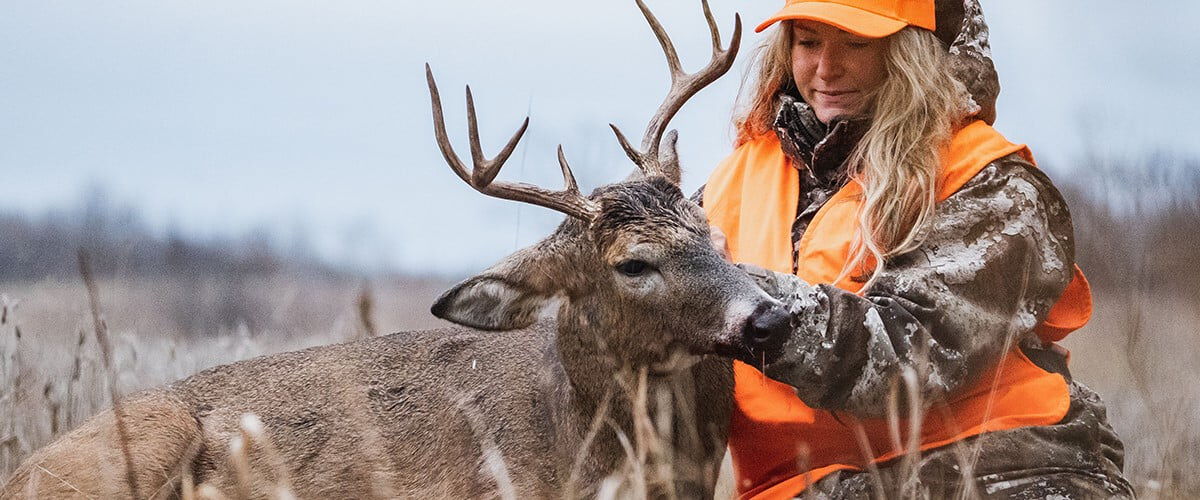 hunter kneeling next to a dead deer