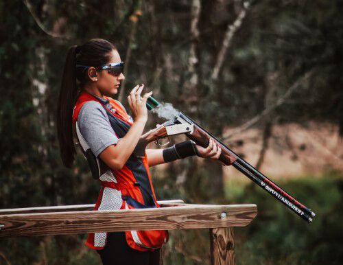 Reanna standing in competition apparel holding a shotgun