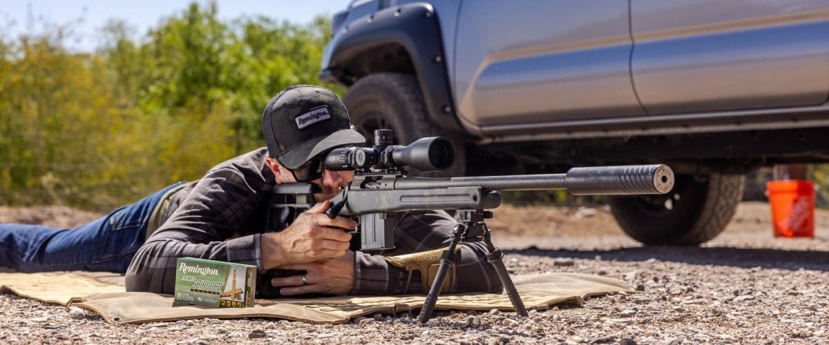Shooting laying on the ground near a pickup looking down a rifle scope