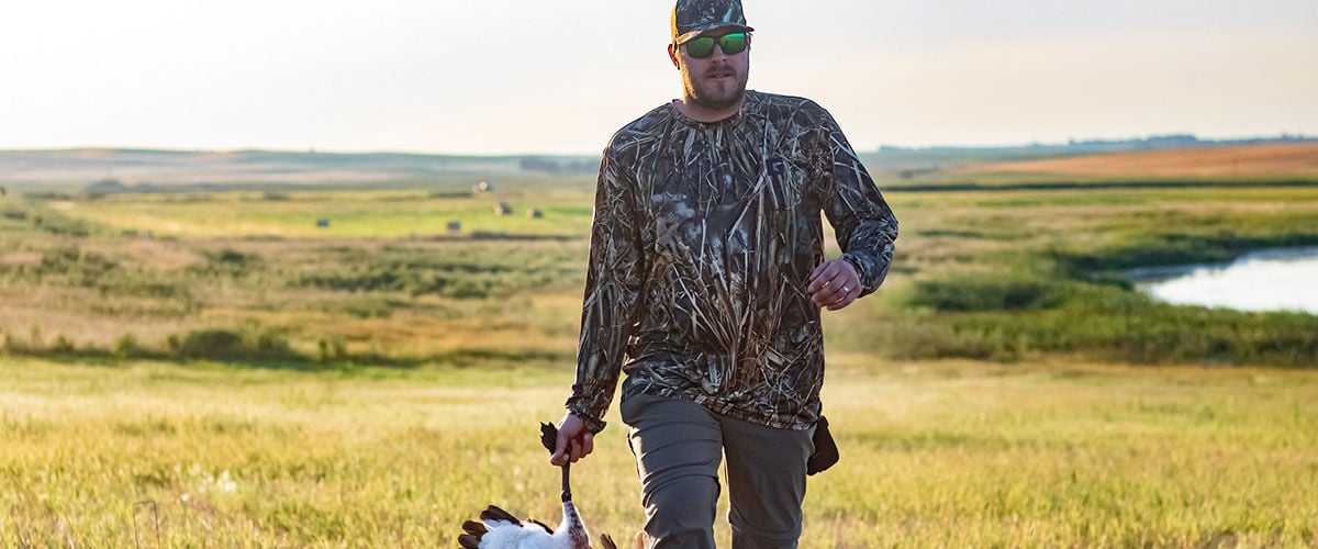 Josh Peck walking in a field while carrying a goose