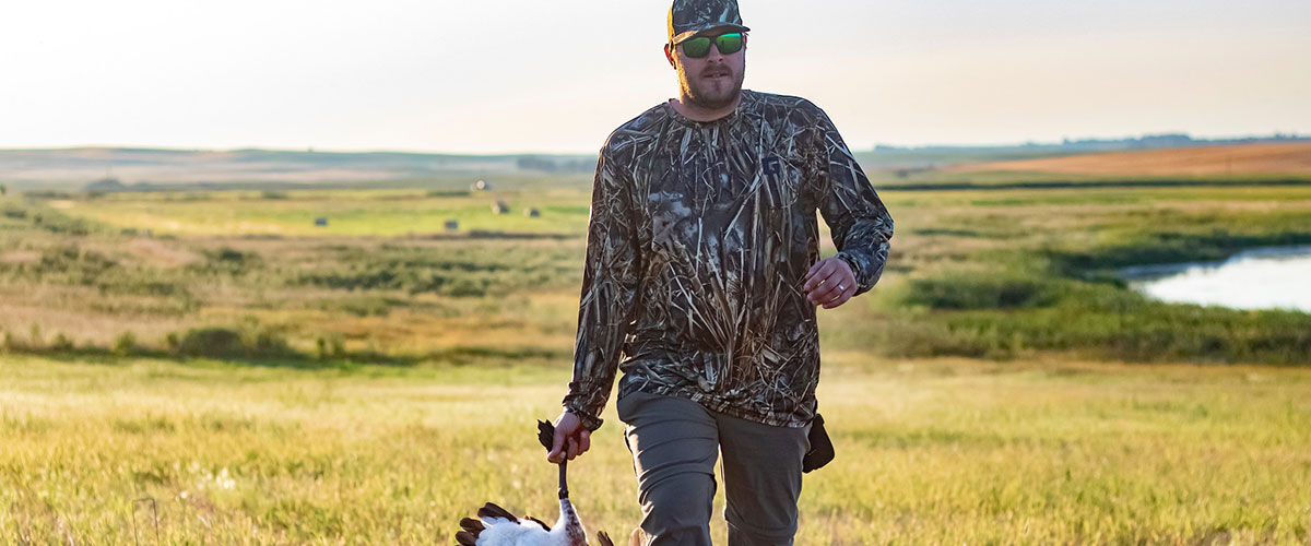 Josh Peck walking in a field while carrying a goose