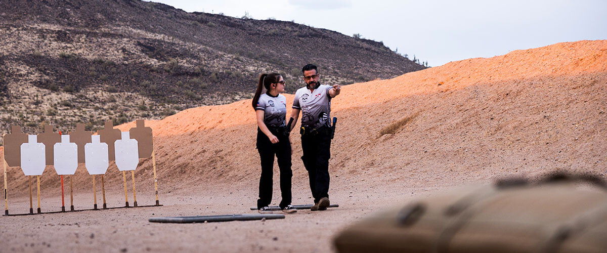 two shooters standing in front of targets on an outdoor range