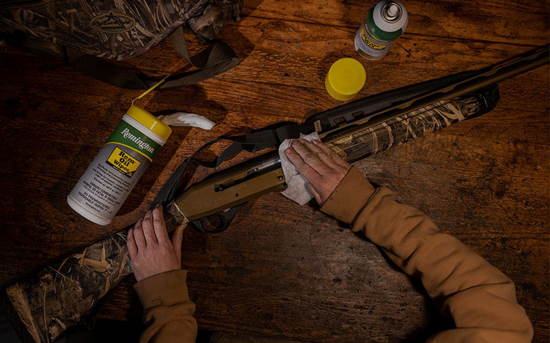 person cleaning gun on bench