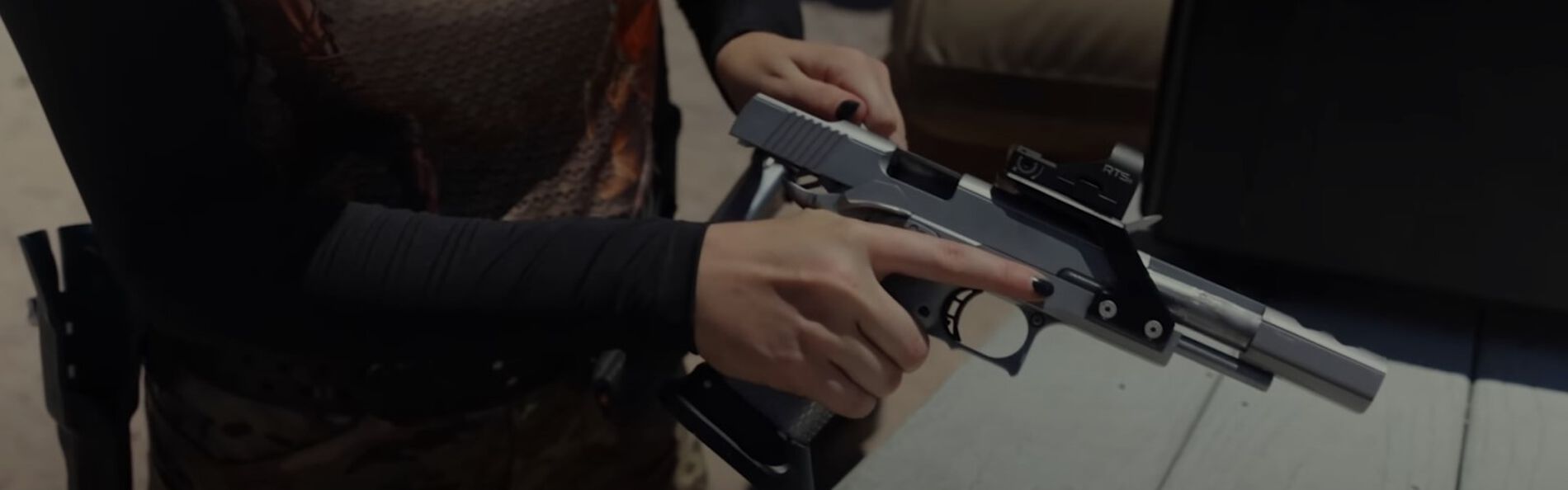 Danyela holding a pistol over a table