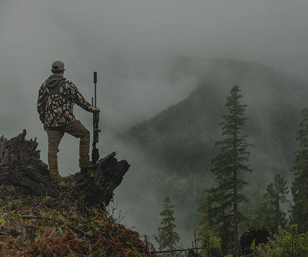 hunter standing in front of a large mountain