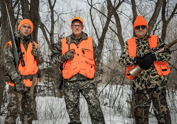 2 hunters standing in the snow with their rifles