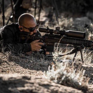 Dustin Sanchez looking down the scope of a rifle