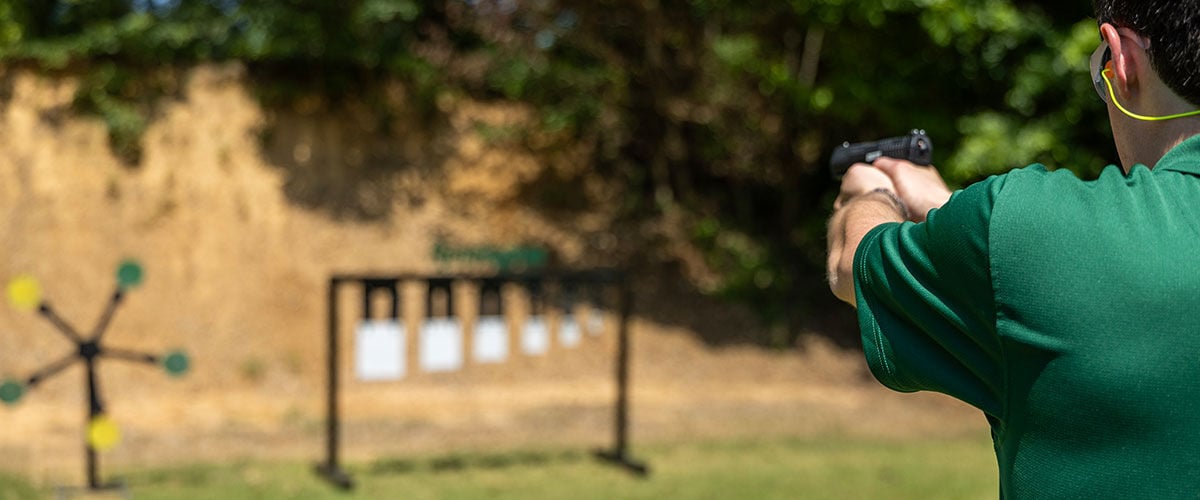 shooter aiming handgun at metal targets outside