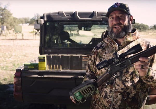 Andy Husek holding a rifle next to an ATV