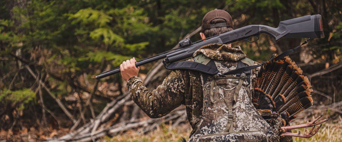 Hunter carrying a rifle on their back and a dead turkey in their backpack