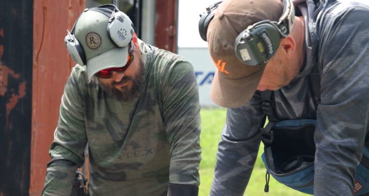 Dustin looking down at a table with a fellow shooter