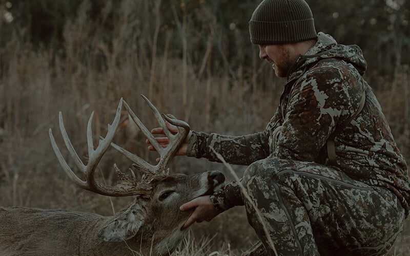 hunter holding up the antlers of a dead deer