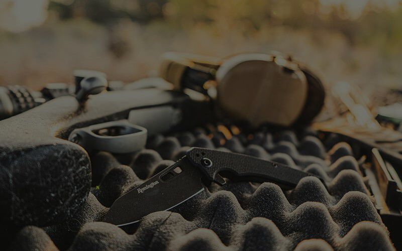 remington knife laying in a gun case with a rifle