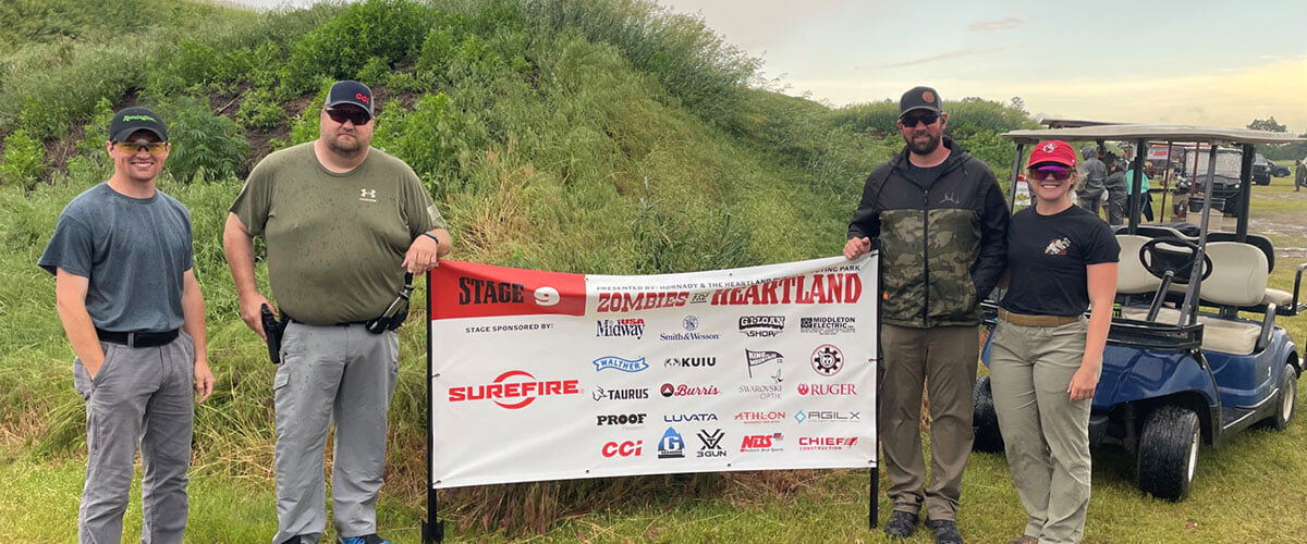 4 shooters standing next to a Zombie Heartland sign