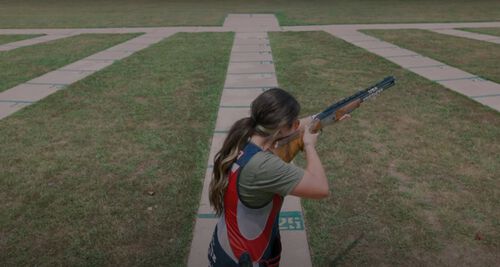 Julia Stallings aiming a shotgun outside at a range