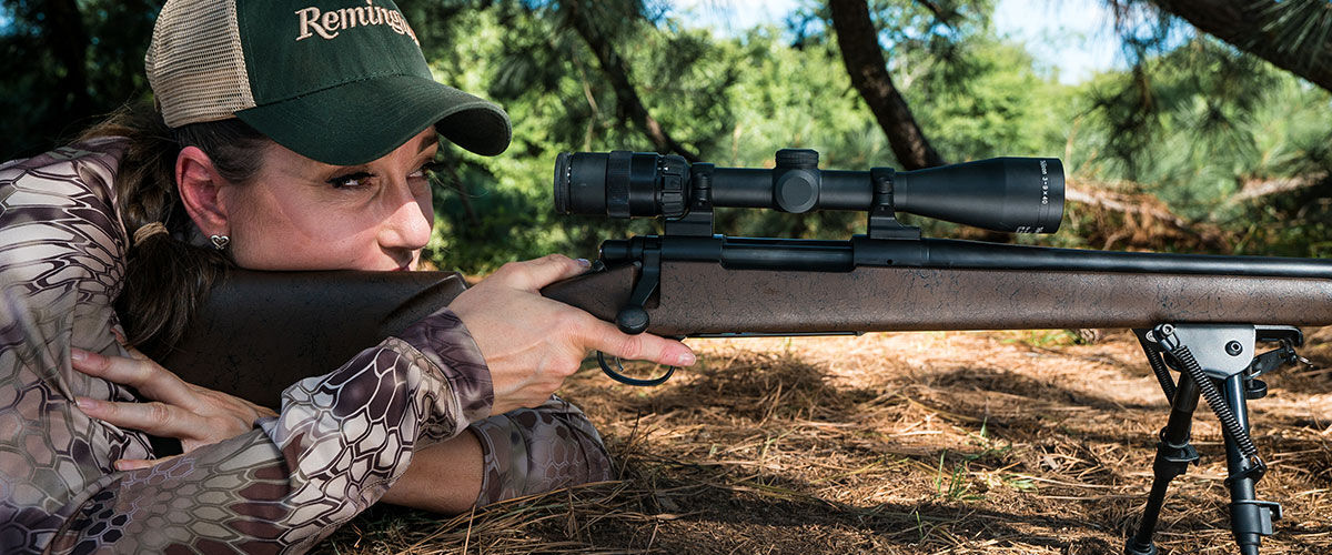 hunter laying on the ground looking through a rifle scope