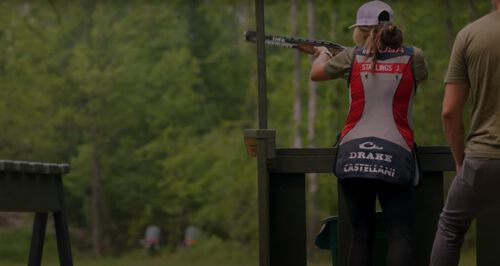 Julia Stallings standing at a shooting stall while aiming her shotgun
