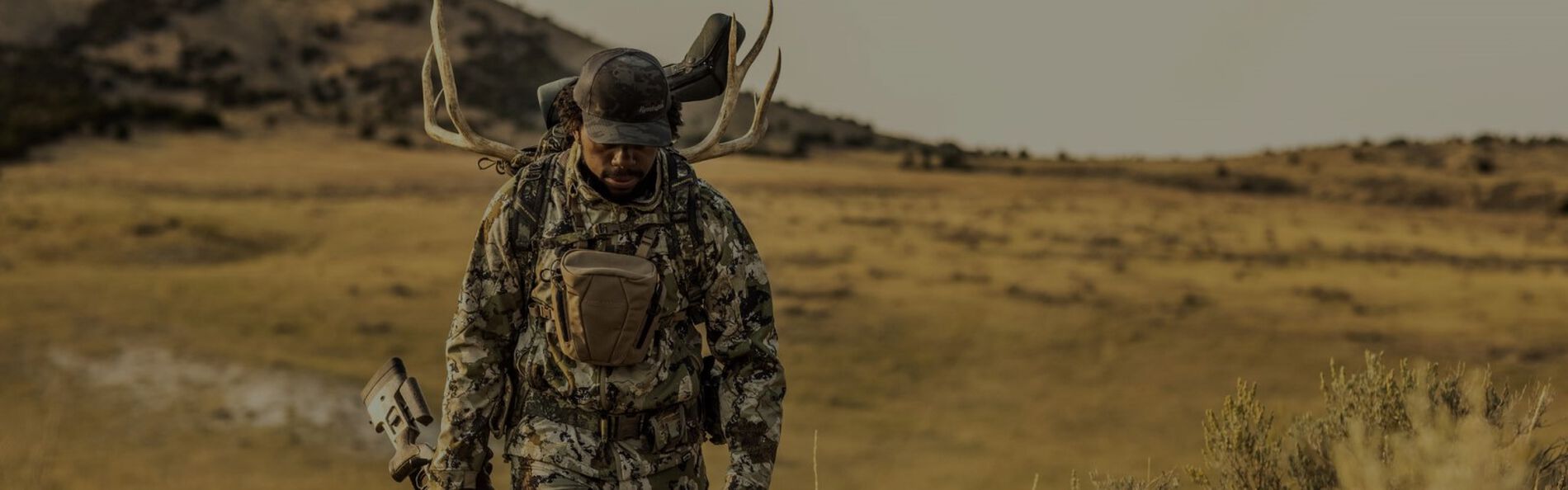 hunter with antlers in his backpack walking on the prairie