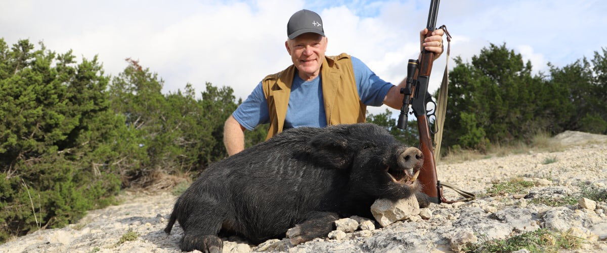 hunter kneeling by a dead boar