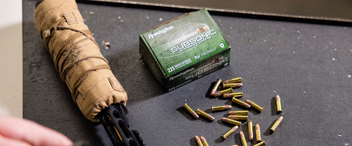 Remington Subsonic box and cartridges next to a suppressed rifle