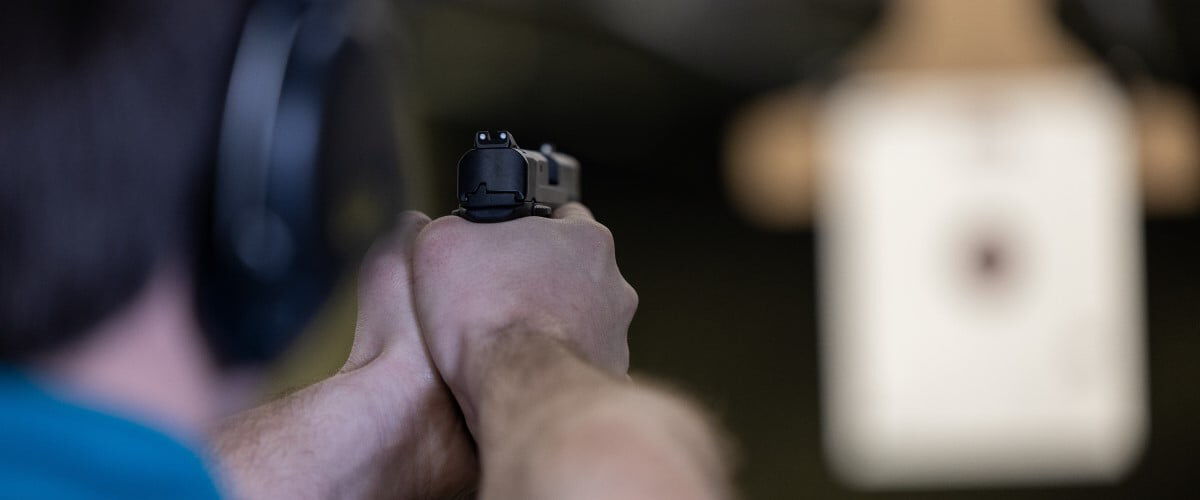 shooter aiming a handgun at a target at an indoor range