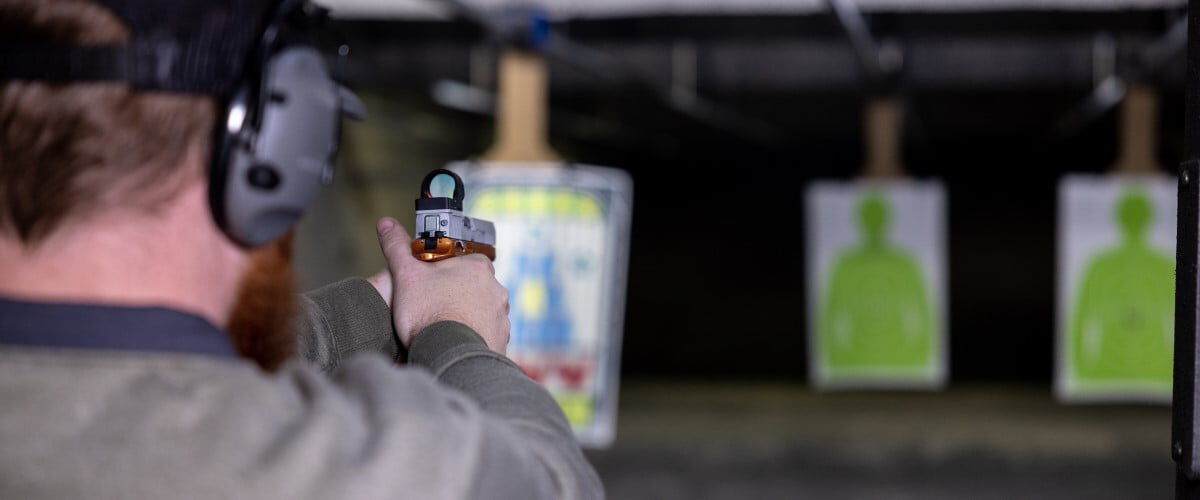 shooter aiming a handgun at a target at an indoor range