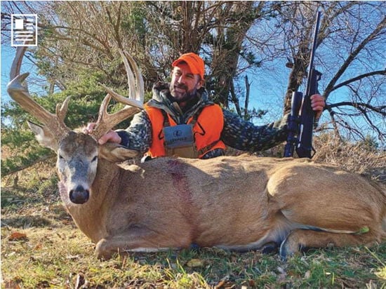 hunter kneeling beside a big buck